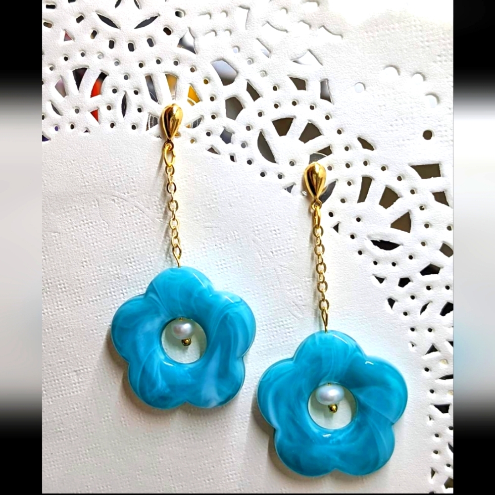 Dangling acrylic teal flowers w/ pearl in the middle. Gold plated chains & studs
